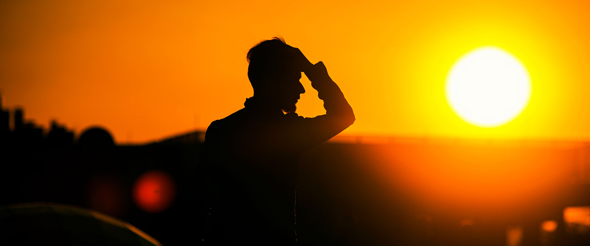 Man holding head sunset